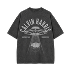 A dark gray mineral-wash t-shirt shown from the back, featuring a large white graphic print of a UFO, a pig, and the text 'CALVIN HARRIS', 'HAMPEN PARK', and 'SUMMER 2026'.